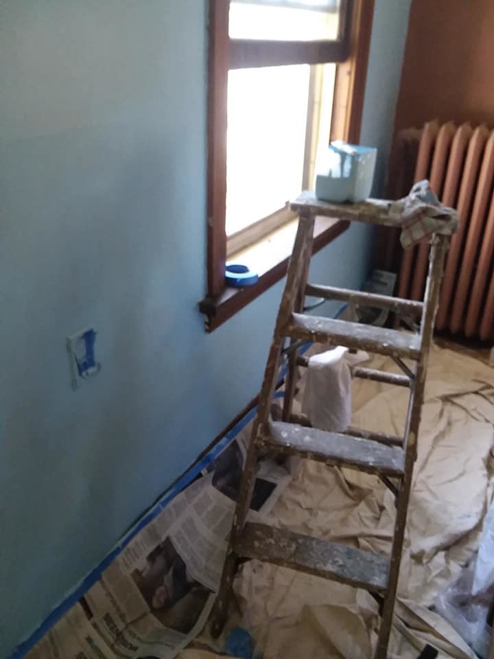 Newly blue bedroom wall, obviously still being touched up with a ladder and paint containers in full view.